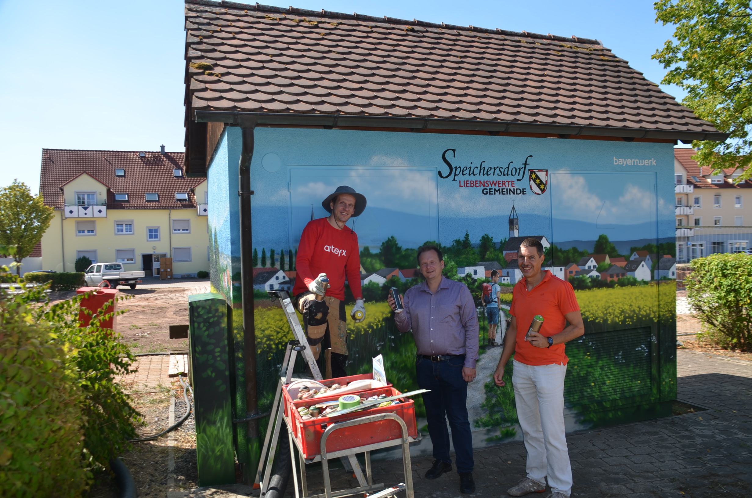 Bemalte Trafostation mit drei Menschen im Vordergrund