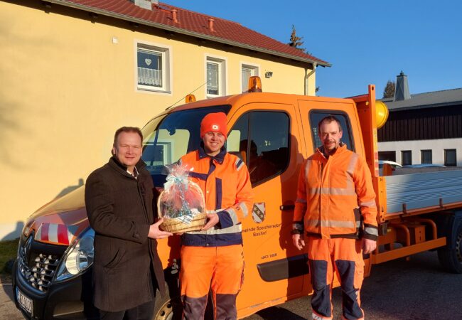 Bürgermeister Chrsitian Porsch übergibt Simon Beer (rechts von ihm) den Wurstkorb. Peter Schlicht steht rechts neben den Beiden.