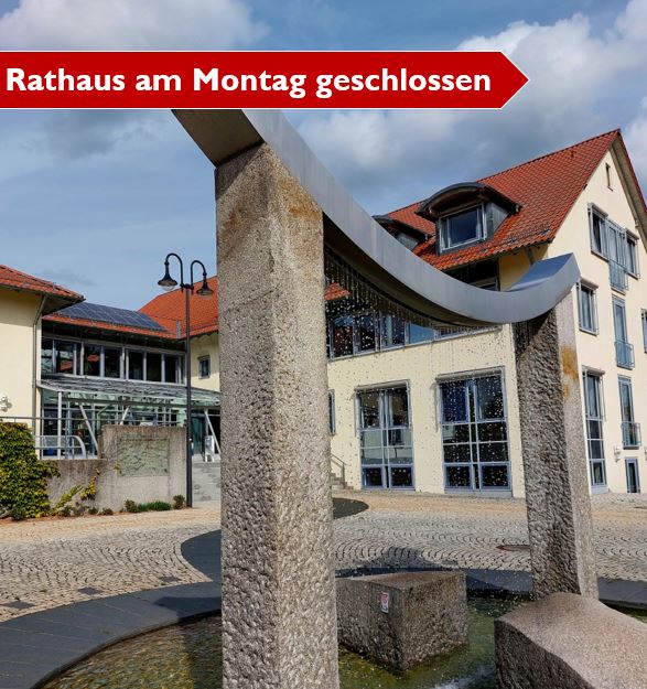 Das Bild zeigt das Rathaus mit Brunnen und ist mit dem Text "Rathaus am Montag geschlossen" beschriftet.