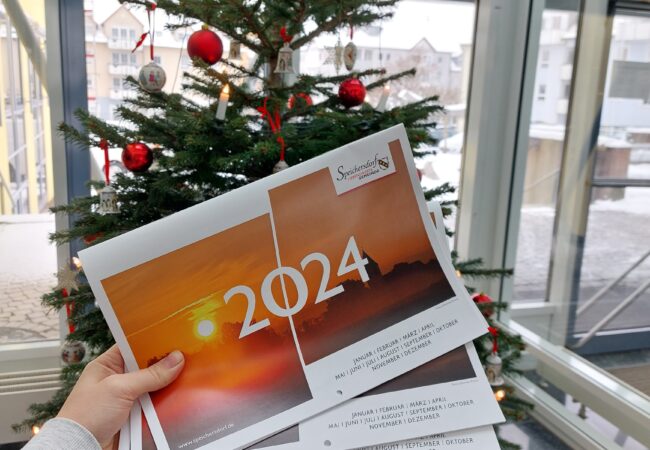 Auf dem Bild ist der neue Speichersdorf Kalender zu sehen vor dem Christbaum im Rathaus.