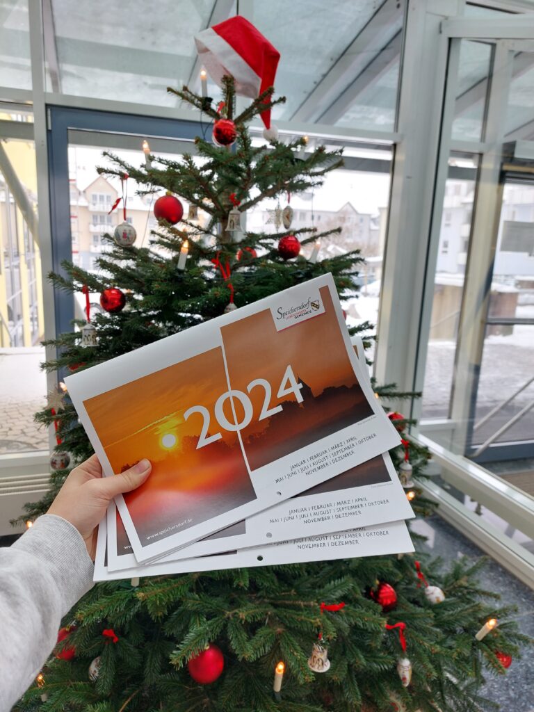 Auf dem Bild ist der neue Speichersdorf Kalender zu sehen vor dem Christbaum im Rathaus.